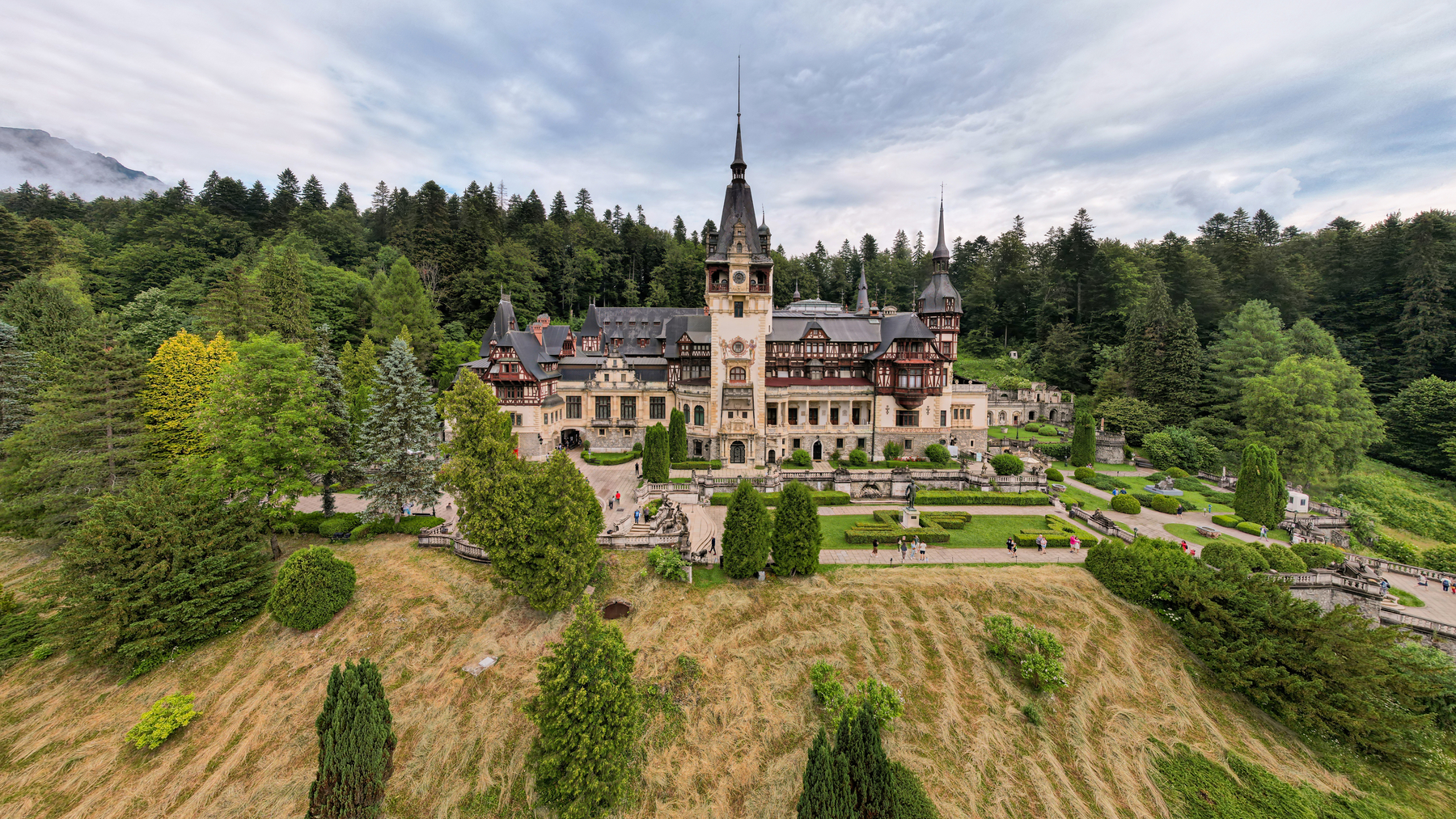Castelul Peleș văzut din curte, cu pădurea și munții în jur